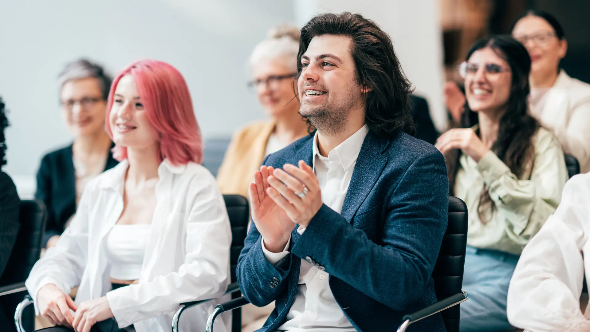 Diverse audience smiling and applauding during a session at the International Conference on Gender and Society