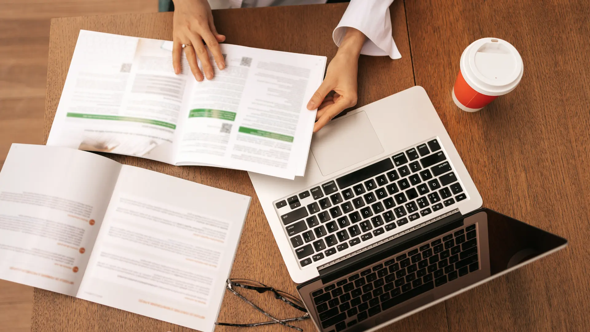 Reviewing printed documents beside a laptop while preparing a submission